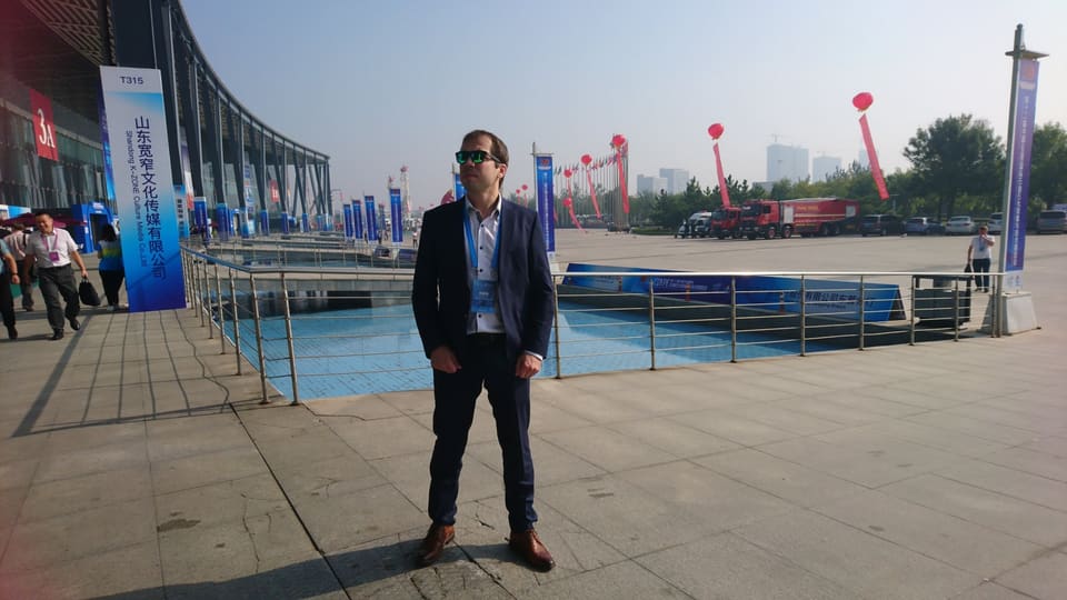 一名身穿深色西装、佩戴参观证的男子在展览中心外。